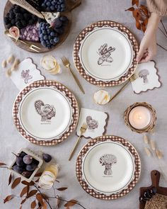 the table is set with plates and silverware, candles, and fruit on it