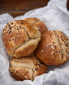 three loaves of bread sitting on top of a piece of wax paper with sesame seed sprinkles