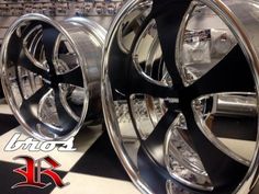 two chrome rims with black spokes are on display at a car showroom