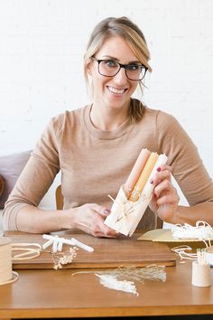 a woman sitting at a table holding a sandwich