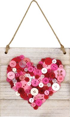 a heart made out of buttons hangs on a string and is hung on the wall