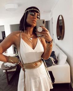 a woman in a white dress taking a selfie with her cell phone and jewelry