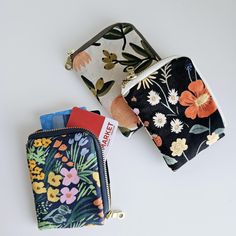 three small zippered pouches with flowers on them, one has a tag in it