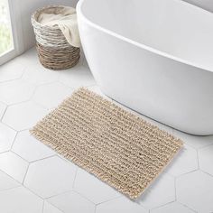 a bath tub sitting next to a window in a bathroom with a rug on the floor