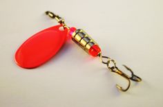 a fishing lure with a red plastic fish hook on it's end is shown