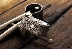 two silver rings sitting next to each other on top of a wooden table with metal handles