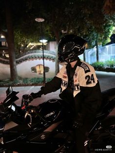 a man sitting on top of a motorcycle in front of a building at night with his helmet on