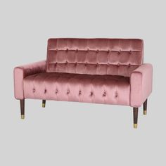 a pink velvet couch with wooden legs and buttons on the arm, against a white background