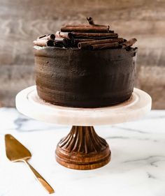 a chocolate cake sitting on top of a white plate next to a wooden spoon and fork