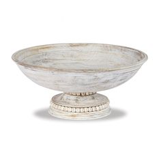 an old white bowl sitting on top of a wooden stand with beading around the rim