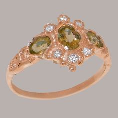 "This traditional accented trilogy ring is made completely of solid Rose Gold, and is set with three vibrant Peridots alongside six dazzling Cubic Zirconia. The ring has a delicate design with a subtle band that is low profile and comfortable to wear, while the face of the ring is is eye catching yet elegant. All the Peridots are natural, earth-mined and therefore have to be individually selected before being hand set into this ring so that they match each other in color and quality. Being hand Red Ring Box, Unique Symbols, Trilogy Ring, Delicate Design, Natural Earth, Yellow Rose, Pink Tourmaline, Precious Metals, Blue Topaz