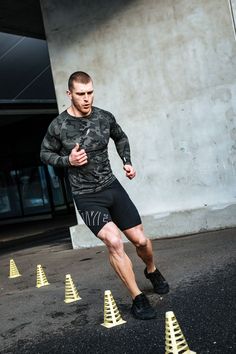 a man in camouflage running through yellow cones