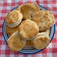 some biscuits on a blue and white plate sitting on a checkered tablecloth covered table cloth