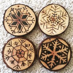 four wooden coasters with snowflakes on them sitting on a carpeted floor