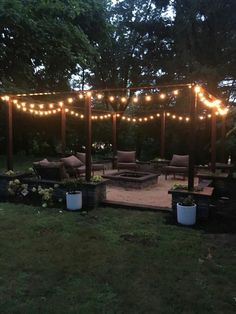 an outdoor patio with lights strung over the fire pit and seating area for people to sit on