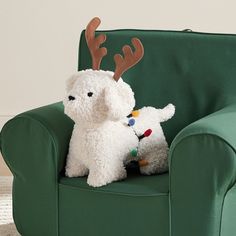 two stuffed animals are sitting on a green chair with reindeer antlers attached to it