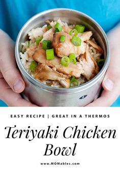 a person holding a metal bowl filled with chicken and green onions on top of rice