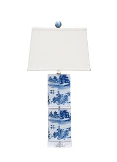 a blue and white table lamp with a shade on the top, in front of a white background