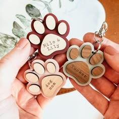 two people holding wooden keychains with dog's paw prints and name on them