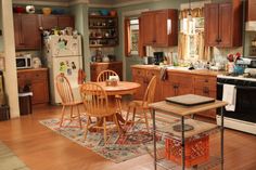 a kitchen filled with lots of wooden cabinets and furniture next to a stove top oven