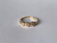 a yellow gold ring with small flowers on the side, sitting on a white surface