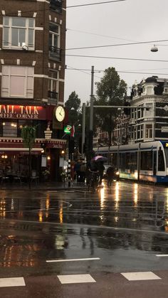 people crossing the street in the rain with umbrellas and a train passing by on a rainy day