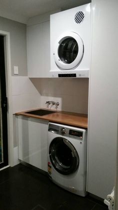 a washer and dryer are in the corner of this small laundry room,