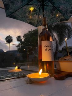 a bottle of wine sitting on top of a table next to a bowl and candle