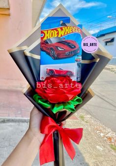 a hand holding a bunch of fake roses with hot wheels stickers on it's side