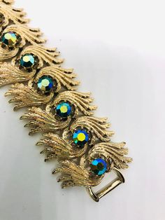 Fabulous vintage signed Coro Pegasus wide rhinestone bracelet. Beautiful blue AB rhinestones set in gold tone/plated textured modernist metal setting. In excellent vintage condition with minimal age appropriate wear.... if any. Doesn't appear to have been worn. Has secure fold over clasp. Stones securely set. Measures 1 3/8 inches wide 7 inches long.   Thanks for looking. Green Metal Bracelet Costume Jewelry, Gold-tone Costume Jewelry Bracelet, Luxury Ornate Cabochon Bracelets, Luxury Ornate Collectible Bracelets, Vintage Filigree Bracelet Collectible, Interchangeable Earrings, Sterling Silver Owl, Vintage Designer Jewelry, Rhinestone Bracelet