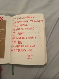 an open book with writing on it and a note attached to the page that says i am learning every day to allow the space between where i am and where i want to be