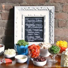 a table topped with bowls filled with food next to a chalkboard