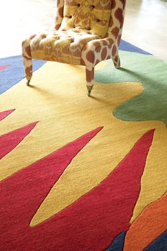 a giraffe print chair sitting in front of a colorful rug on the floor