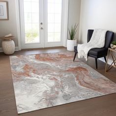 a living room area with a rug, chair and potted plant on the floor