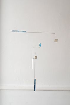 a white wall with a blue object hanging from it's side in the corner