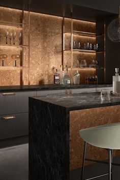 a modern kitchen with marble counter tops and black cabinets, along with wine glasses on the shelves