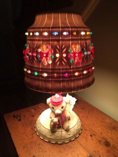 a teddy bear sitting on top of a table next to a lamp shade that has lights all over it