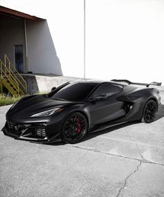 a black sports car is parked in front of a building with stairs on the side