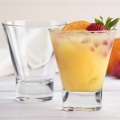 two glasses filled with fruit sitting on top of a white table next to each other