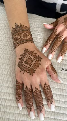 two hands with henna tattoos on them, one is white and the other is brown