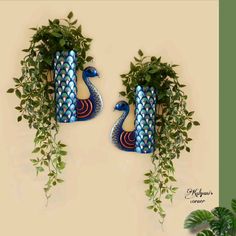 two blue vases with green plants in them on a white wall next to each other