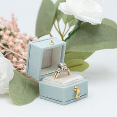 an engagement ring in a box next to flowers