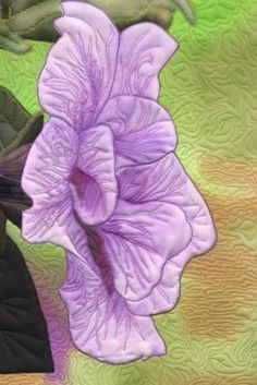 a purple flower sitting on top of a green and yellow quilt