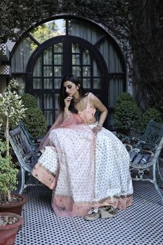 This peach and white poly paper silk lehenga has glitter flower motifs spread all over.  It is paired with an embroidered raw silk blouse and an embroidered net dupatta. White Raw Silk Lehenga With Pallu, Peach Chanderi Sets With Sheer Dupatta, White Tissue Silk Set With Sheer Dupatta, Festive White Raw Silk Lehenga, White Semi-stitched Raw Silk Lehenga, White Raw Silk Choli For Diwali, Semi-stitched White Raw Silk Lehenga, Designer Tissue Silk White Lehenga, Designer White Tissue Silk Lehenga