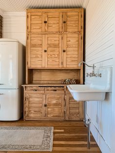 a white sink sitting next to a wooden cabinet in a room with wood flooring