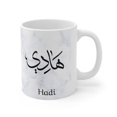 a white marble coffee mug with the word hadi in arabic