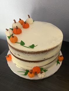 a three layer cake decorated with pumpkins and leaves