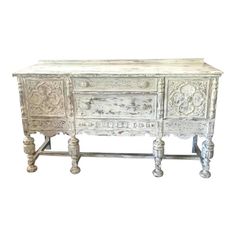 an old white dresser with ornate carvings on the top and drawers, sitting against a white background