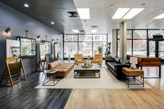 a living room filled with lots of furniture next to tall windows on the wall and wooden floors