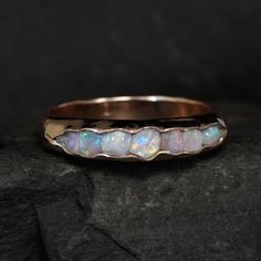 a gold ring with white opal inlays sitting on top of a rock